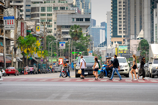 Thailand-April 10: Vehicle are waiting traffic light and crow of people are walking cross zebra way on April 10,2021 at Asoke-Sukhumvit intersection in Bangkok,Thailand