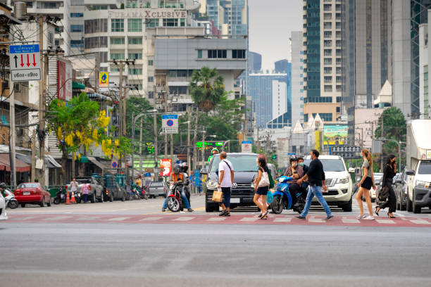 Asok intersection ,Bangkok Thailand-April 10: Vehicle are waiting traffic light and crow of people are walking cross zebra way on April 10,2021 at Asoke-Sukhumvit intersection in Bangkok,Thailand bangkok street stock pictures, royalty-free photos & images