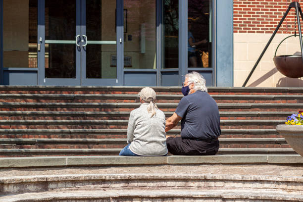 先輩の白人カップルは、covid-19パンデミックの間に手をつないで公園に座っています。 - holding hands couple senior couple togetherness ストックフォトと画像