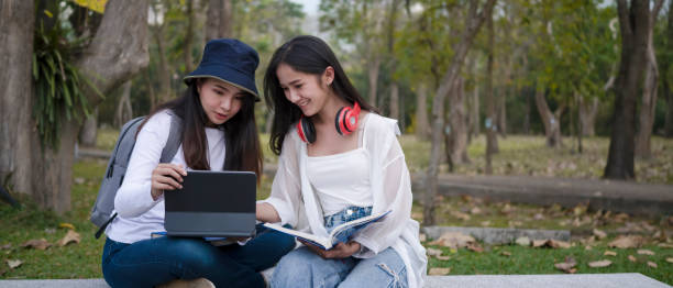 istock Two students sitting together on bench in the campus and using digital tablet during break. 1312051023