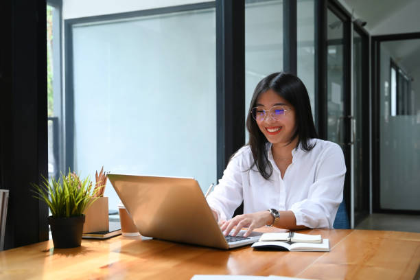 istock Happy young woman office worker smiling and working on laptop computer in office. 1312051078