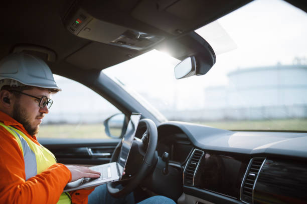 istock Engineer using a laptop in his car in front of oil rafinery. 1312052803
