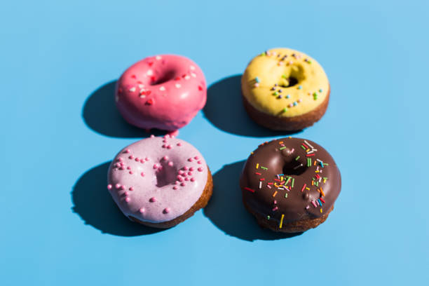 istock Colourful round donuts at bright blue background. Sweet donuts. Trendy sunlight Summer pattern Minimal summer concept. 1312057076