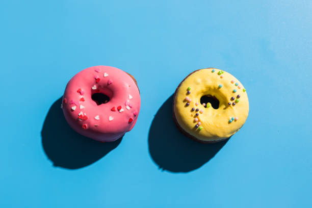 istock Colourful round donuts at bright blue background. Sweet donuts. Trendy sunlight Summer pattern Minimal summer concept. 1312057082