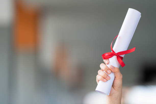 Close-up shot of a university graduate holding a degree certification to shows and celebrate education success on the college commencement day. Education stock photo stock photo