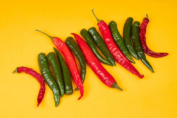istock Red and green hot chili peppers on yellow background 1312058417