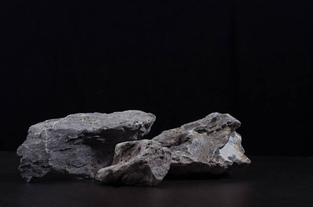 istock Grey marble stone podium for packaging and cosmetic presentation on black background, copy space. Natural and strong style. 1312058726
