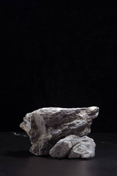 istock Grey marble stone podium for packaging and cosmetic presentation on black background, vertical. Natural and strong style. 1312059474