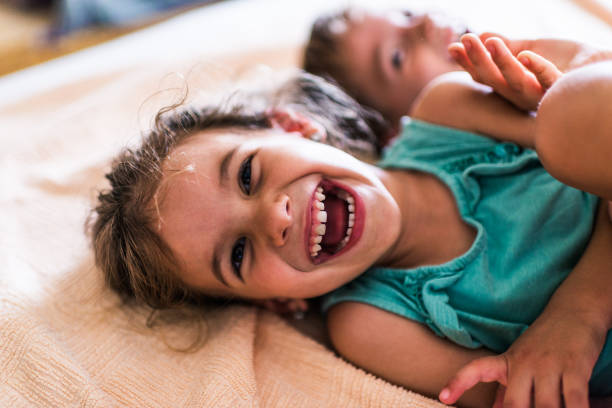 Beautiful children playing on the bed Little boy and his sister are playing on the bed. children laughing stock pictures, royalty-free photos & images