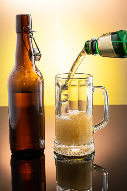 istock pouring beer into beer glass from bottle on yellow background 1312060288