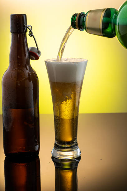 istock pouring beer into beer glass from bottle on yellow background 1312060878