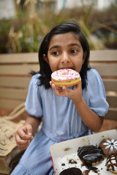 Girl sitting outdoors and eating a doughnut