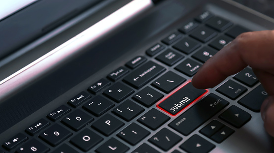 User finger press laptop keyboard button with SUBMIT word. Concept for business and e-commerce. Selective focus
