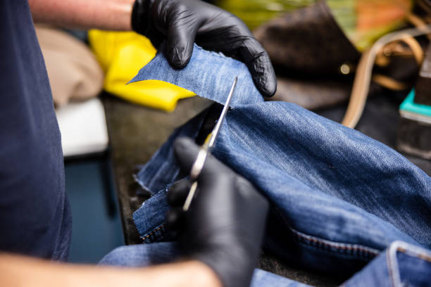 istock Cutting a piece of denim with scissors for patch from old jeans legs 1312065012