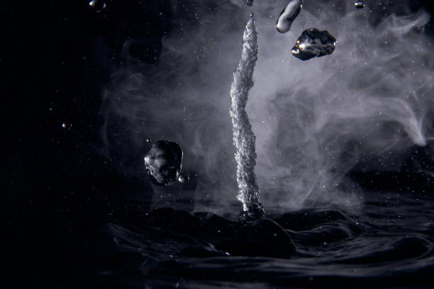istock Boiling water splash with steam on black background closeup 1312066395