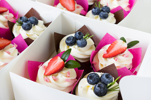 Cupcakes  decorated with strawberry and blueberries  in delivery paper box. Sweet food delivery