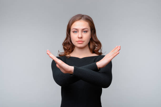 istock Serious young brunette woman showing stop gesture while looking at camera. Studio shot, gray background 1312067195