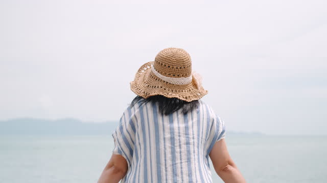 Asian woman walking and standing and looking sea view and thinking and feeling calm in summer vacation