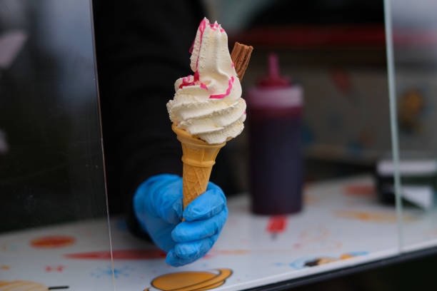 Ice cream in a cone. A fluffy white ice cream in a cone with raspberry sauce and chocolate stick. ice cream van stock pictures, royalty-free photos & images