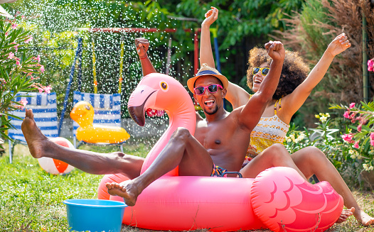 Afro Couple having staycation fun on back yard with inflatable pink flamingo