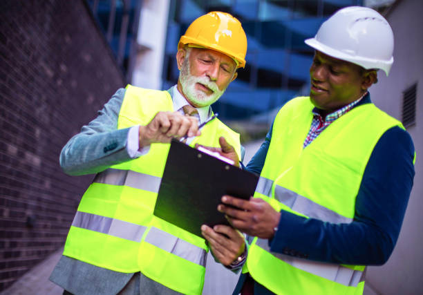 istock Mature engineer discussing the structure of the building with architects colleague at construction site. Reading document. 1312073883