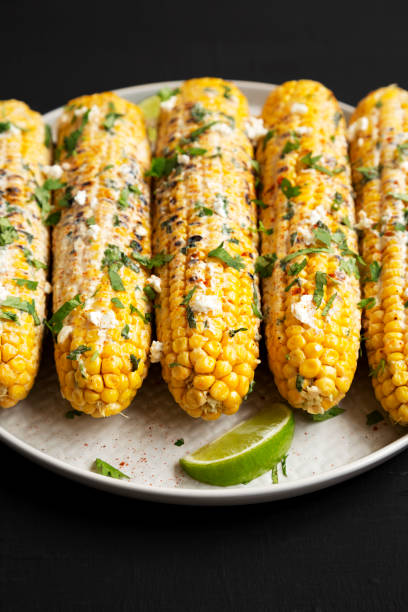 istock Homemade Elote Mexican Street Corn on a plate on a black surface, low angle view. 1312075724