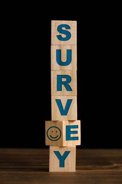 Survey written on wooden toy blocks with smiley face Wooden toy blocks are rotating on the wooden table over black background. Survey written on the cubes with a smiley face. Survey concept. Vertical composition with copy space. anthropomorphic smiley face photos stock pictures, royalty-free photos & images