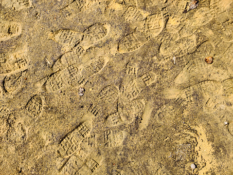 Footprints of boots on the wet sand. Texture of prints, background wallpaper dirty sand after rain. High quality photo