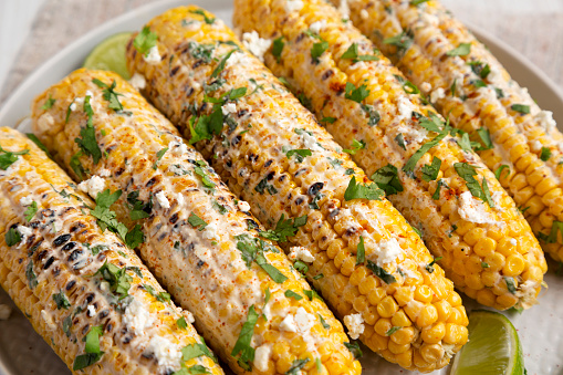 Homemade Elote Mexican Street Corn on a plate, side view. Close-up.
