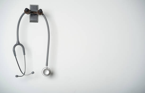 stethoskop ausrüstung des arztes mit hängt auf dem weißen wandhintergrund mit kopierraum für medizinisches und medizinisches konzept - hängen grafiken stock-fotos und bilder