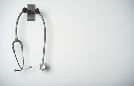 stethoscope equipment of doctor with is hanging on the white wall background with copy space for healthcare and medical concept