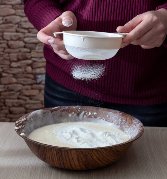 istock Hands hold a sieve, sifting flour into a bowl of dough. Selective focus. 1312080809