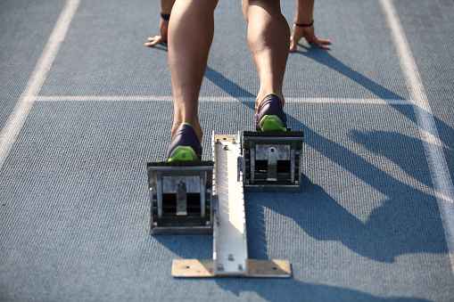 Athlete adjusting starting block at track and field stadium.