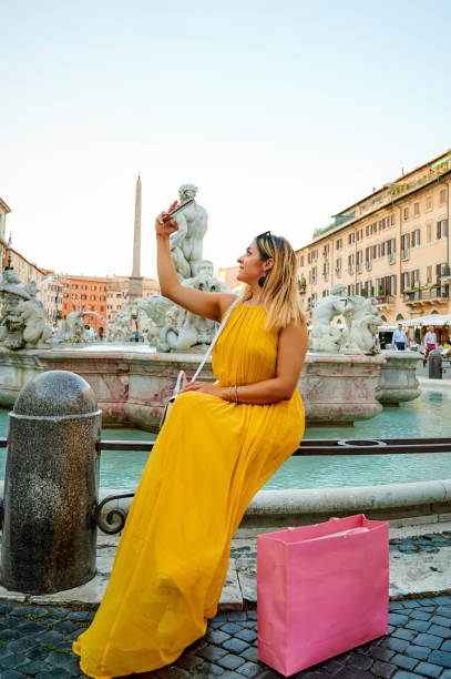 Some journeys can only be travelled alone Shot of a young woman taking a selfie in front of the Fontana del Moro in the Piazza Navona, Rome Italy fontana del moro stock pictures, royalty-free photos & images