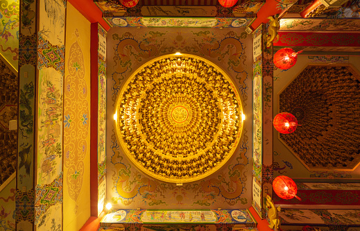 Bottom view of golden chandelier hanging ceiling golden light with red lamp lanterns in Chinese temple. Circle square frame. Decoration painting.