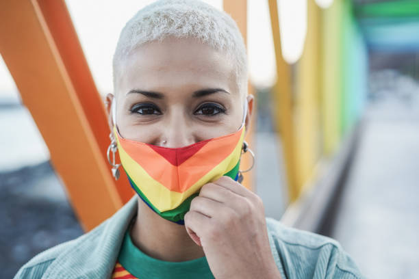 istock Young lesbian smiling on camera while wearing rainbow mask - Focus on face 1312092028