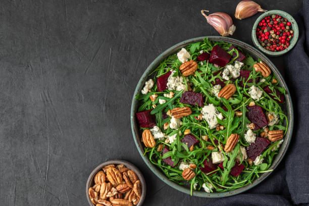 istock Arugula, beet and blue cheese salad with pecan nuts in a plate on black table background. top view with copy space 1312094871