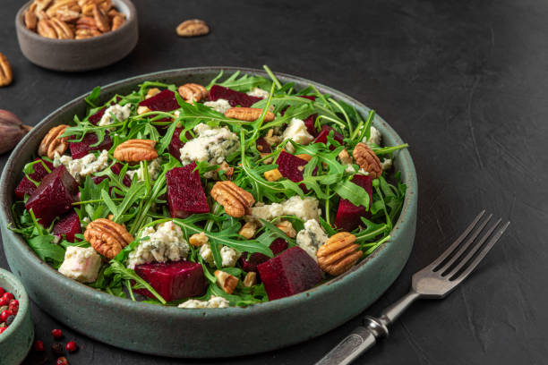 istock Arugula, beet and blue cheese salad with pecan nuts in a plate with fork on black table background. healthy vegetarian food 1312094936