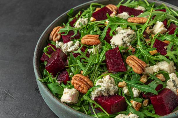 istock Beet or beetroot salad with fresh arugula, blue cheese and pecan nuts in a plate on black background. close up 1312094950
