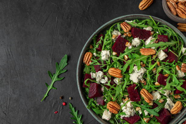 istock Salad with fresh arugula, beetroot, gorgonzola cheese and pecan nuts in a plate on black background. top view 1312094992