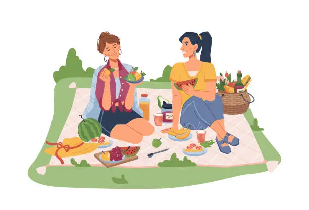Vector illustration of Female friends sitting on blanket on picnic, seating fruits and snacks. Vector sandwiches, juice and soda drink, bananas, basket with fruits and vegetables, spoon and hat, communicating girls