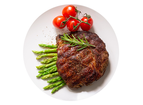 plate of grilled steak with rosemary and asparagus isolated on a white background, top view