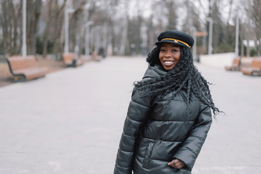 Photo portrait of cheerful black skinned girl. Afro girl walking in city park. Lifestyle