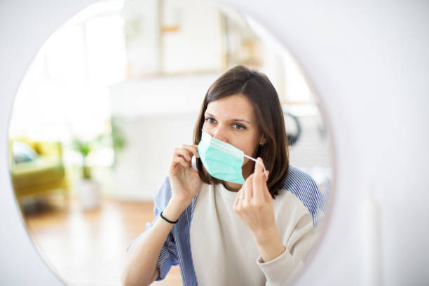 istock Young woman putting on mask before mirror 1312101525