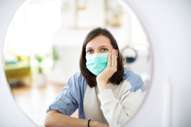 istock Young woman putting on mask before mirror 1312101591