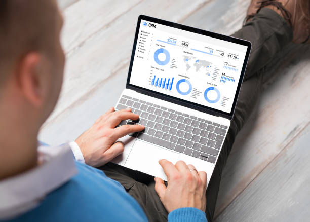 istock Man using CRM software on laptop with different graphs and charts showing sales data for his business 1312101786