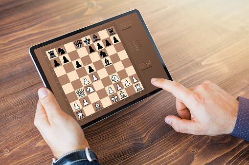 Man taking a rest and playing chess online on tablet computer