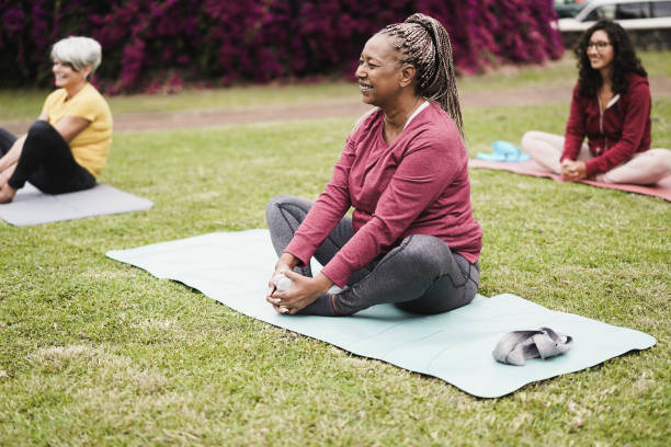 happy people doing yoga class keeping social distance at city park - focus on african woman face - senior adult relaxation exercise healthy lifestyle exercising imagens e fotografias de stock