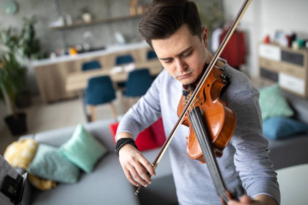 istock Violinist tuning the strings before playing violin at home 1312104686