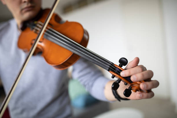 istock Violinist tuning violin at home 1312104703